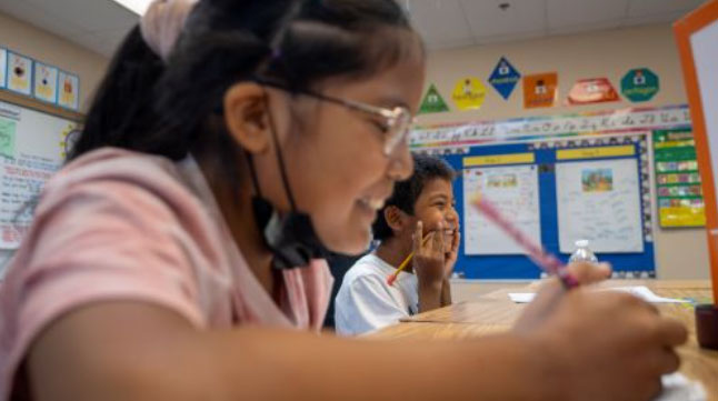 Two students working at their desk in classroom.