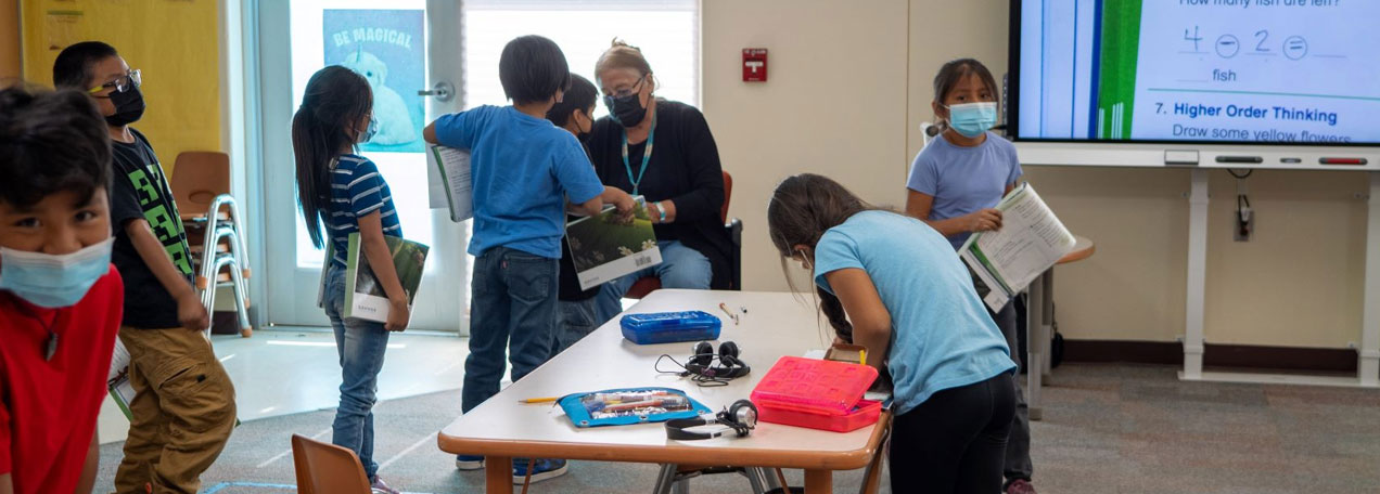 Students standing in a line to show the teacher their work. 