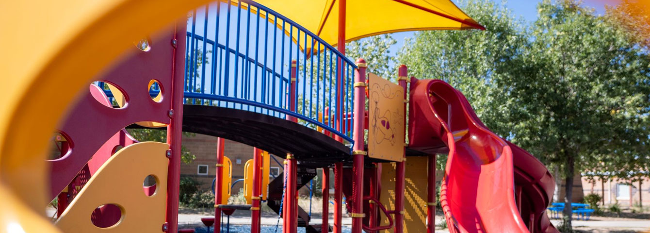 Yellow school outdoor playground with red slide.
